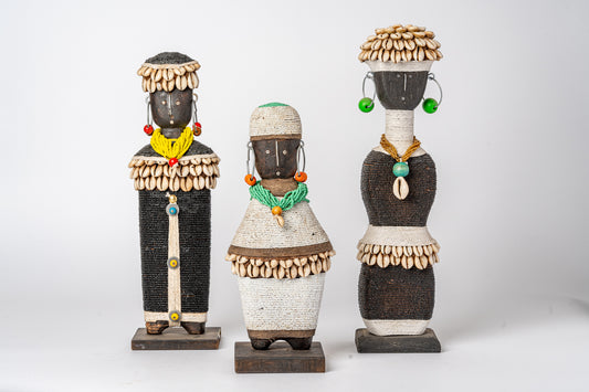 Three decorative dolls with carved wooden heads, woven fiber bodies, shell bead headdresses, and colorful beaded accessories 