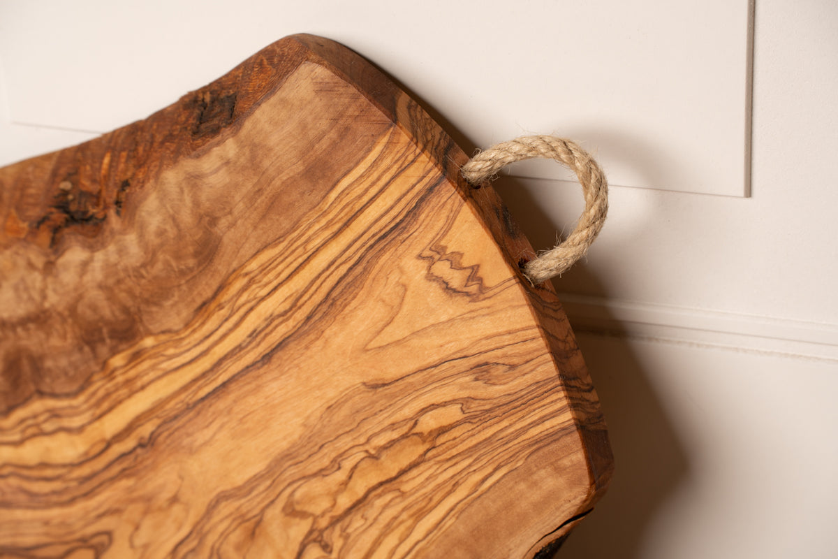 Wooden charcuterie board with natural grain patterns and a rope handle.