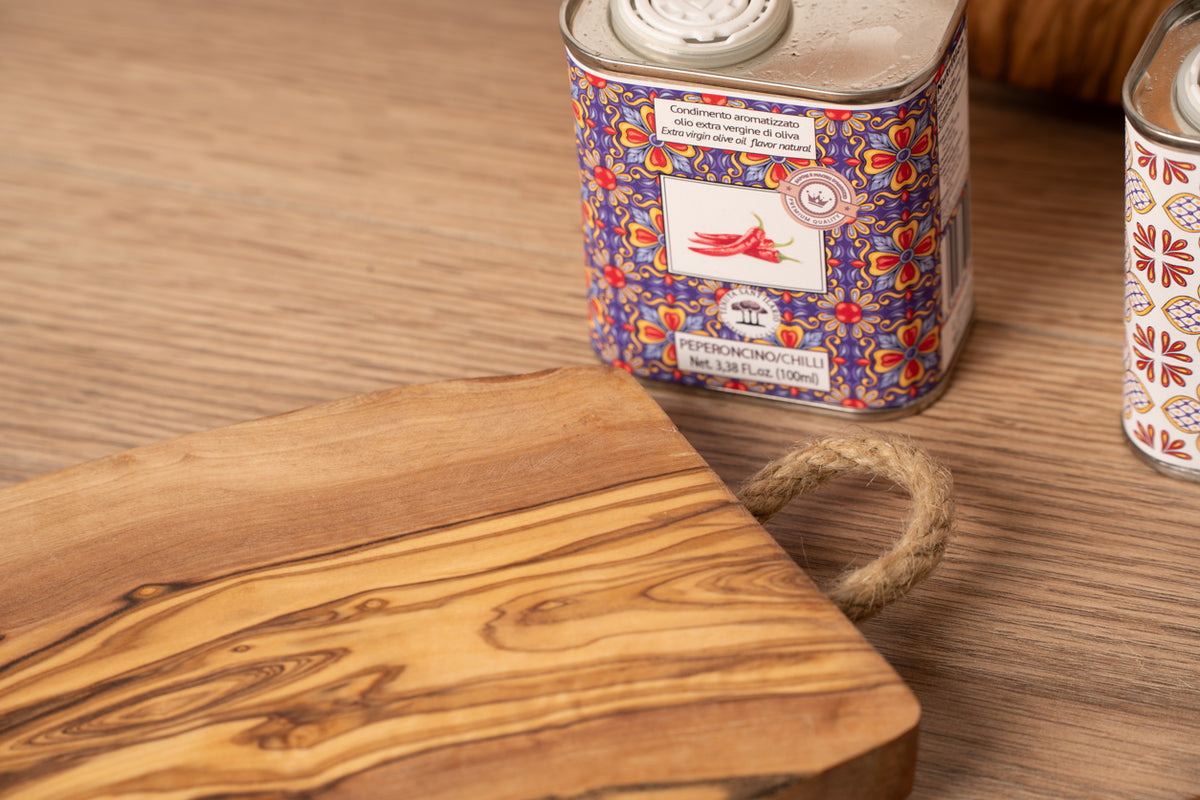 Olive wood charcuterie board with natural grain patterns and attached rope handle.