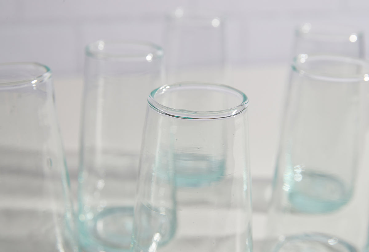 Six clear glass cone-shaped champagne glasses with teal-tinted bases arranged in a group.