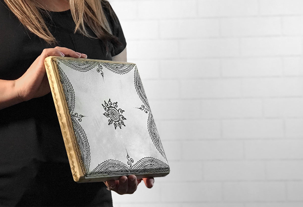 Square frame drum with white vellum head featuring black geometric and floral patterns, wooden rim.