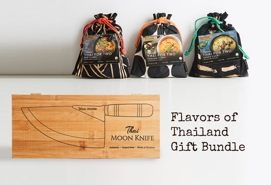 Three fabric pouches with curry meal kits and a bamboo cutting board with Thai moon knife displayed against white background.