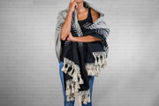 Black and cream striped blanket with fringe trim draped over person's shoulders.