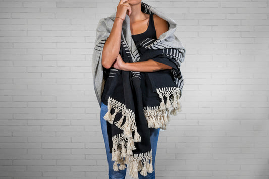 Black and cream striped blanket with fringe trim draped over person's shoulders.