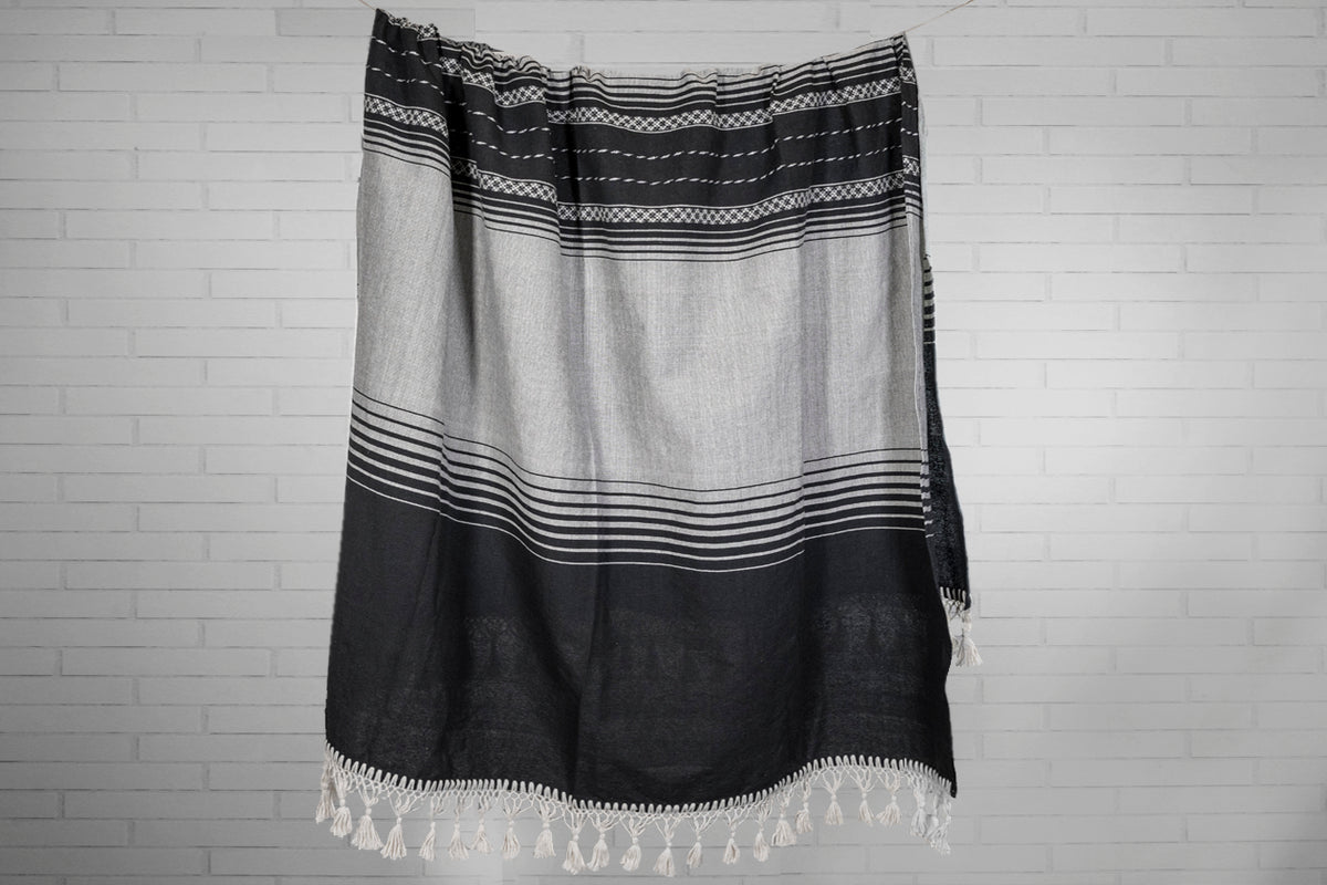 Black and cream striped woven blanket with geometric patterns and white fringe trim.