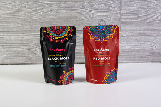Two Los Pacos mole sauce pouches: black mole on left, red mole on right, with colorful mandala designs on packaging.