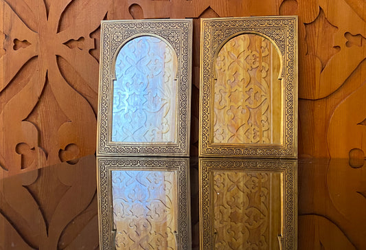 Two rectangular mirrors with ornate metal frames and geometric carved panels, one with blue-tinted glass and one with gold-to
