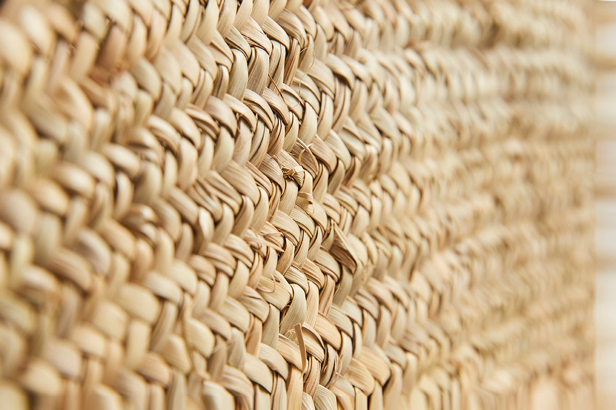 Close-up of woven natural straw material with diagonal weave pattern in tan color.