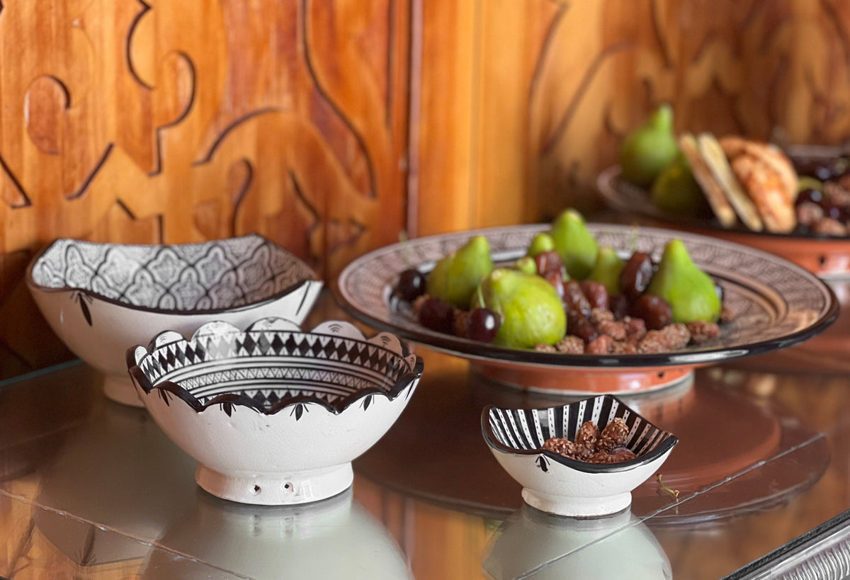 Set of four ceramic nesting bowls with geometric black patterns on cream and terracotta surfaces.