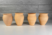 Four terracotta clay cups with wide mouths and rounded bodies arranged in a row.