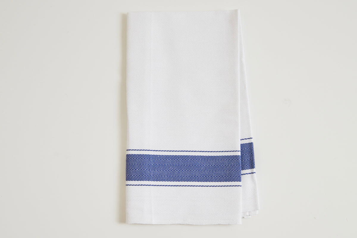 White kitchen towel with navy blue herringbone stripe detail across the center.