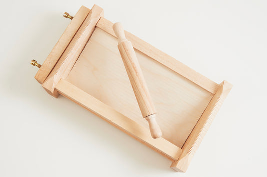 Wooden pasta chitarra with parallel strings and detachable rolling pin for making fresh pasta.