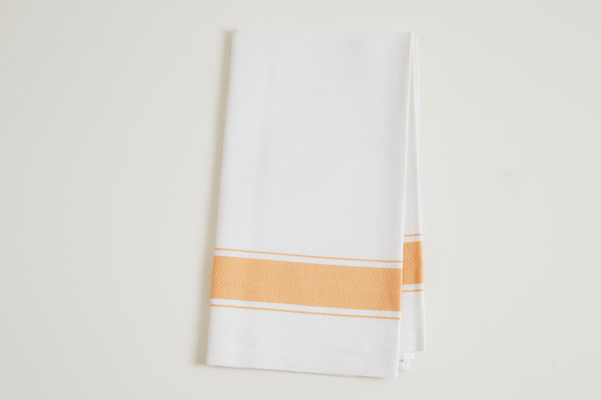 White kitchen towel with herringbone weave and orange and white stripe accent band.