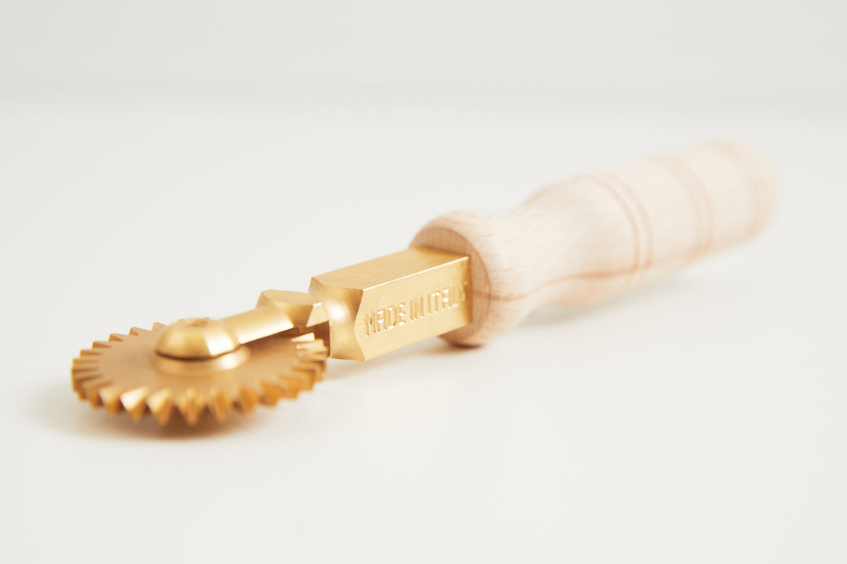 Brass fluted wheel cutter with cream-colored handle and engraved brass shaft.
