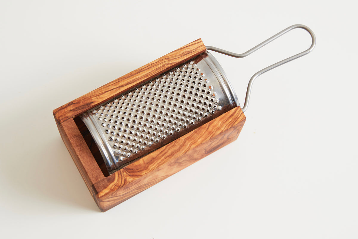 Box grater with stainless steel grating surface and wooden olivewood handle with metal loop.