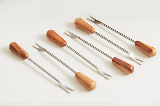 Six small forks with wooden handles in varying shades of brown and metal tines arranged in rows.