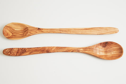 Two wooden spoons with olive wood grain pattern and rounded bowls displayed side by side.