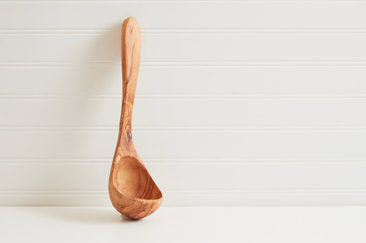 Wooden ladle with round bowl and long handle carved from light brown olivewood.