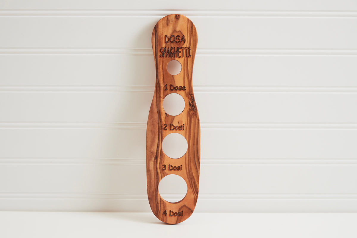 Wooden spaghetti measurer with four circular holes labeled 1 Dosi through 4 Dosi for portioning pasta.