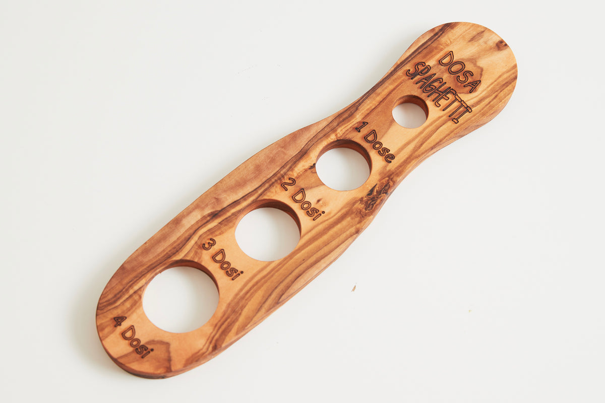 Wooden spaghetti measurer with four circular openings labeled with portion sizes, made from light brown olivewood with engrav