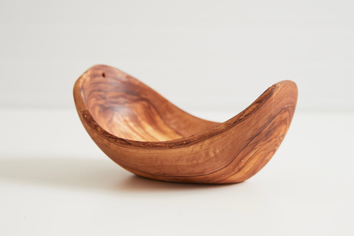 Brown wooden serving bowl with curved oval shape and natural grain pattern throughout.