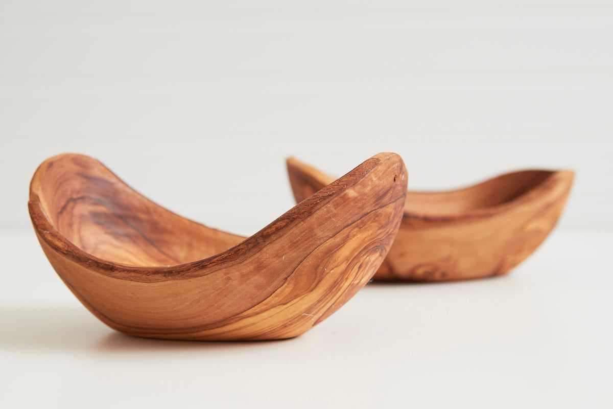 Two curved olivewood serving bowls with natural grain patterns and warm honey-brown finish.