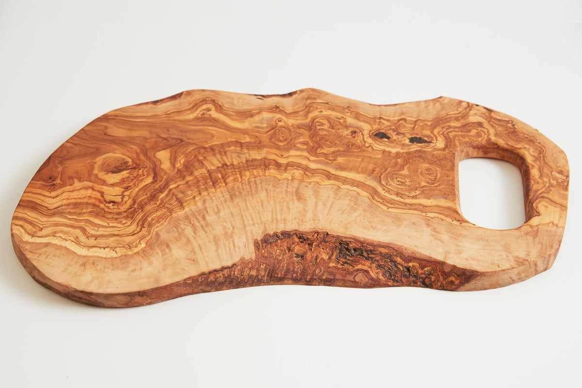 Large olivewood cutting board with natural wood grain patterns and a handle cutout on one end.