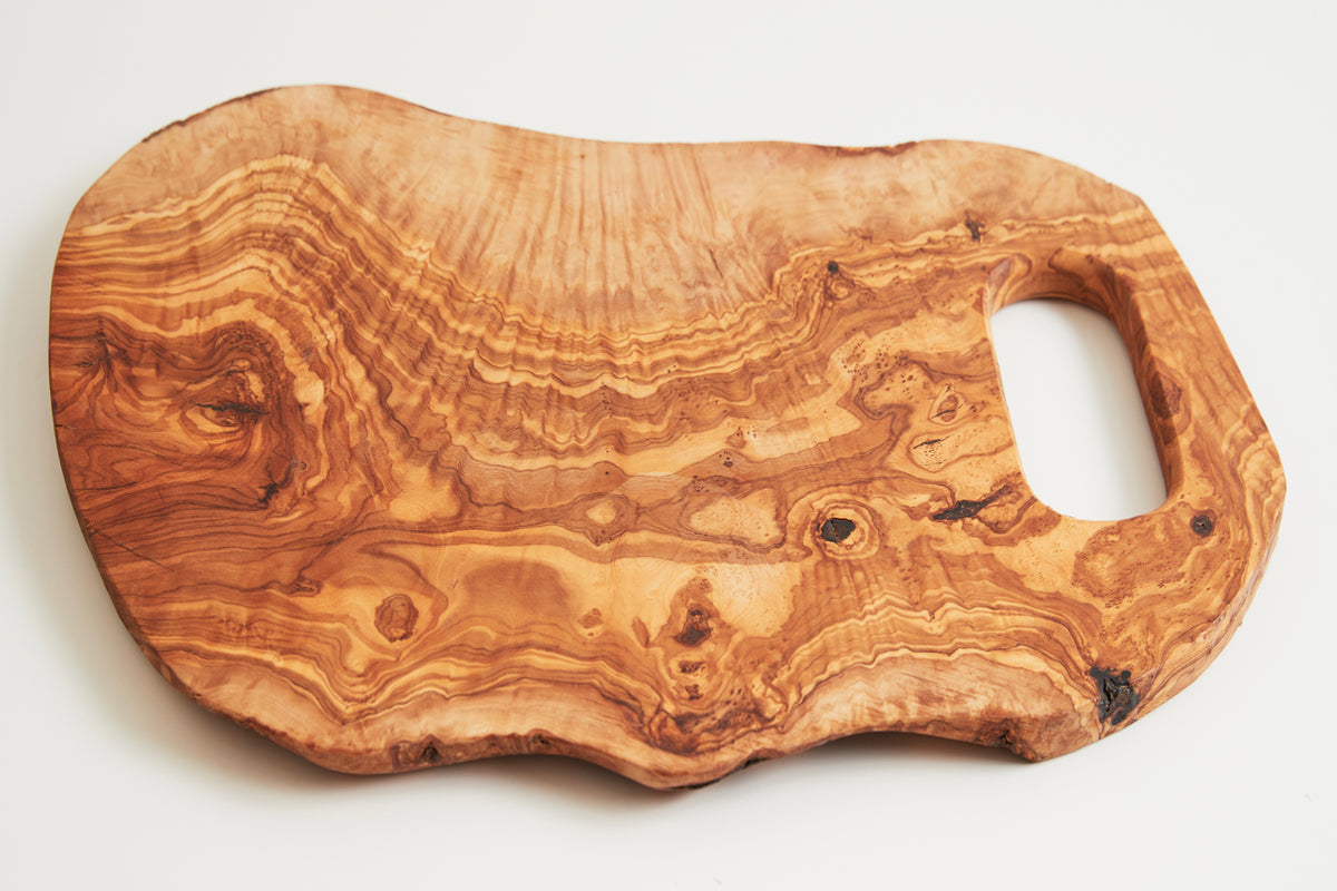 Large wooden charcuterie board with natural grain patterns, irregular edges, and handle cutout.