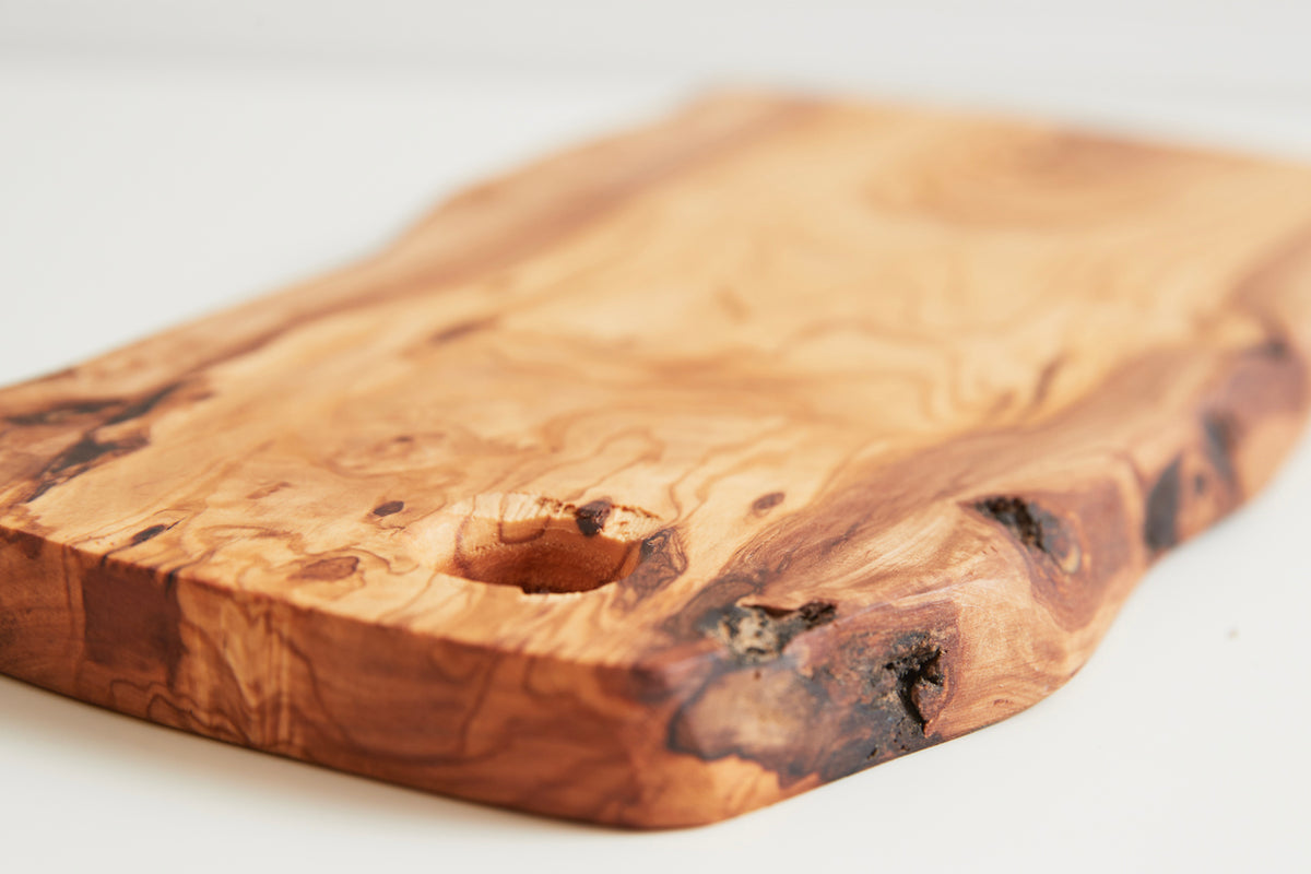Olive wood charcuterie board with natural grain patterns and a single hole for hanging.