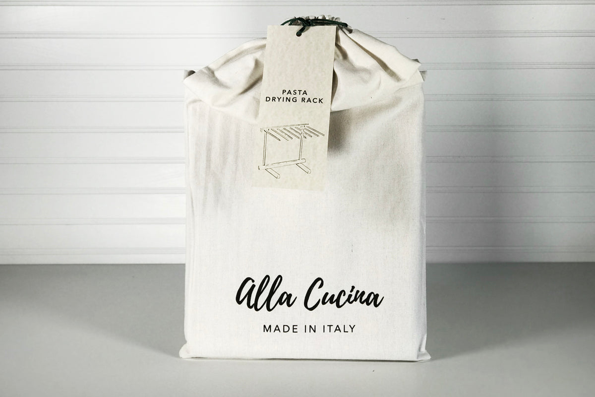 Pasta drying rack packaged in cream-colored cloth bag with black text and product tag.