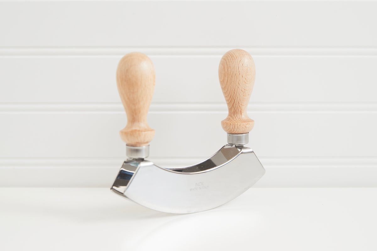 Double-bladed curved knife with two wooden handles connected by a metal crescent-shaped blade.