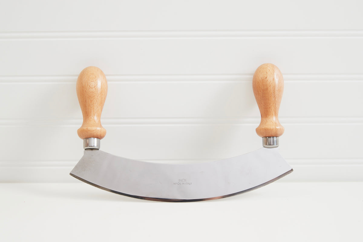 Large mezzaluna with curved stainless steel blade and two wooden handles with metal ferrules.