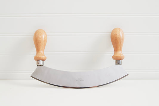 Large mezzaluna with curved stainless steel blade and two wooden handles with metal ferrules.