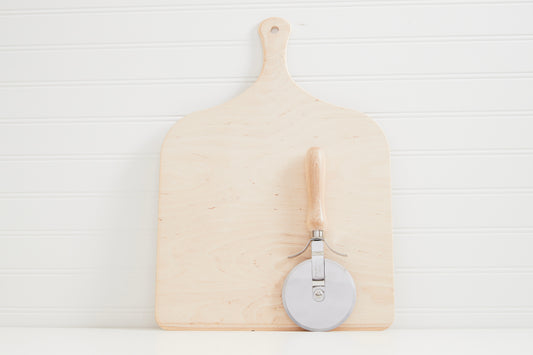 Wooden pizza peel with handle and metal pizza cutter with wooden grip on white background.