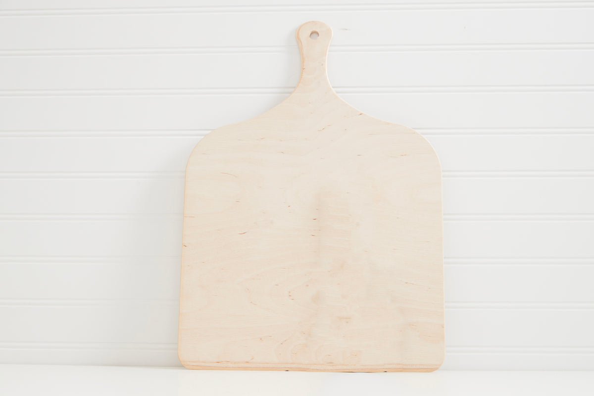 Wooden pizza peel with rounded handle and flat shovel-shaped surface on white background.