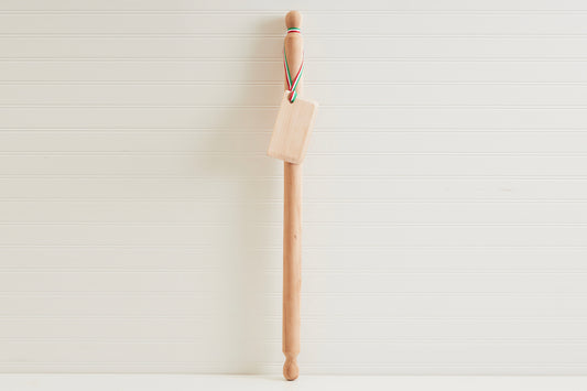 Wooden mattarello pasta rolling pin with handles at both ends and a rectangular dough scraper attached by twine.