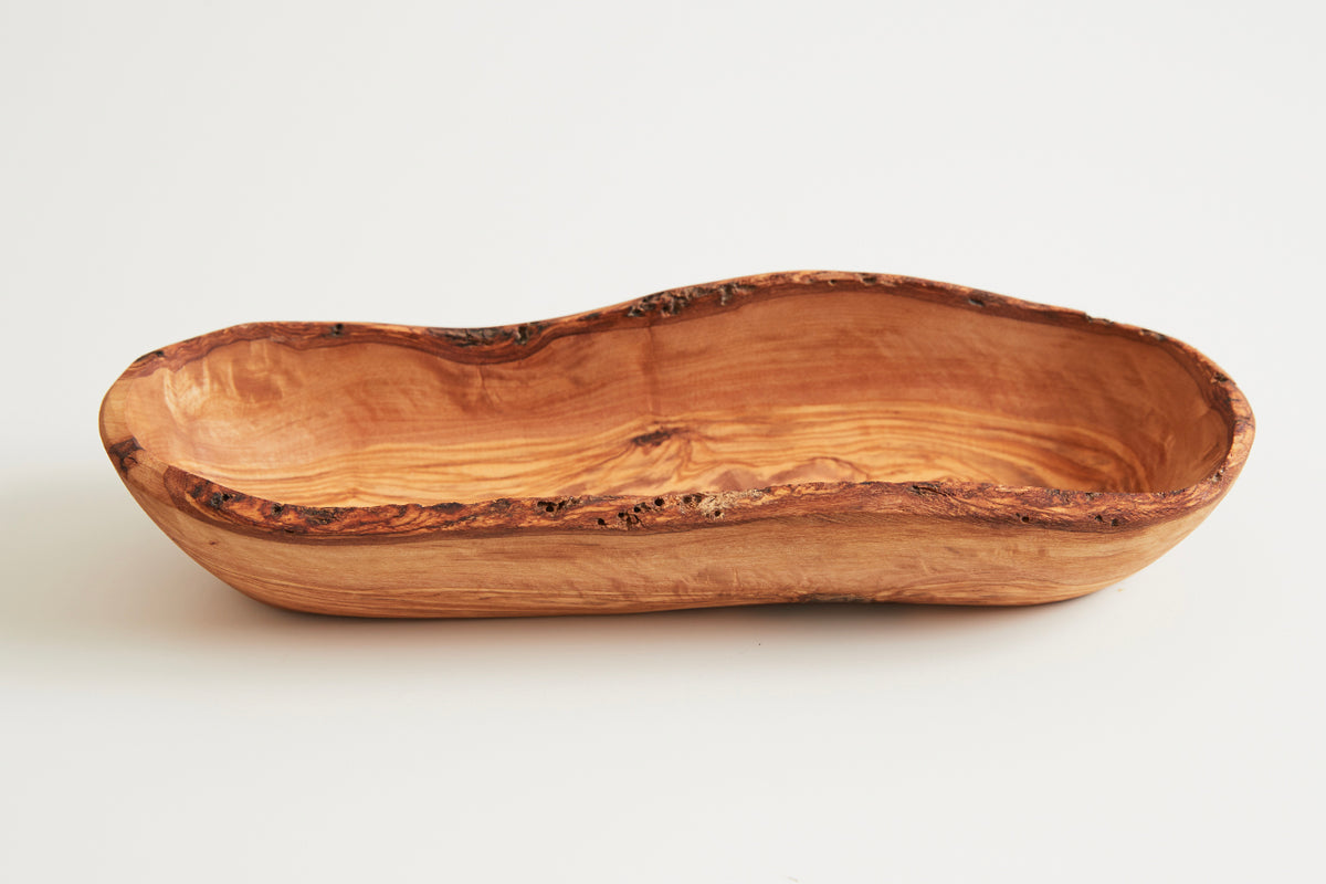 Elongated wooden boat bowl with natural tan finish and dark bark-edged rim.