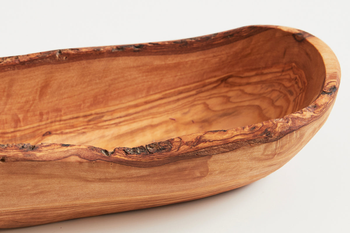 Wooden boat-shaped bowl with natural live edge and grain patterns visible throughout the interior and exterior.