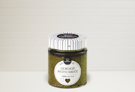 Jar of green Genovese pesto sauce with white and black striped lid and white label on neutral background.