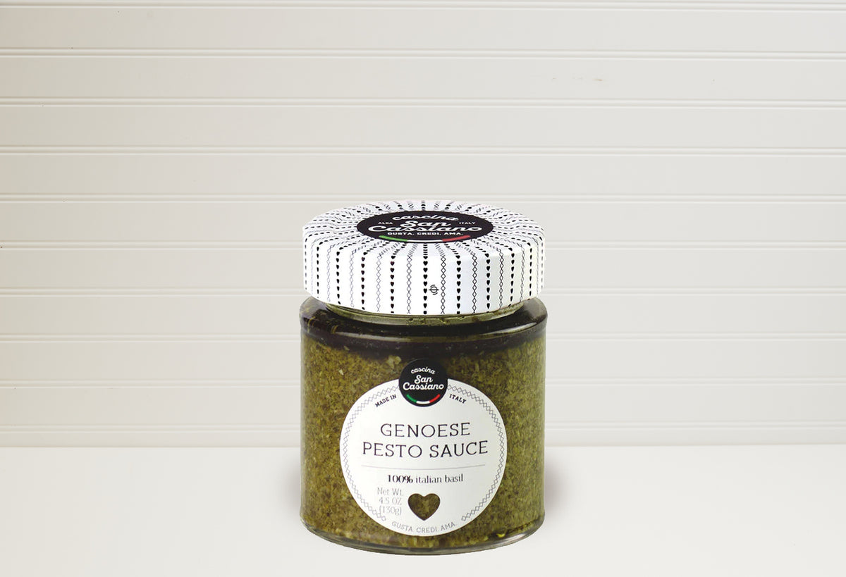 Jar of Genoese pesto sauce with white and black striped lid on white background.
