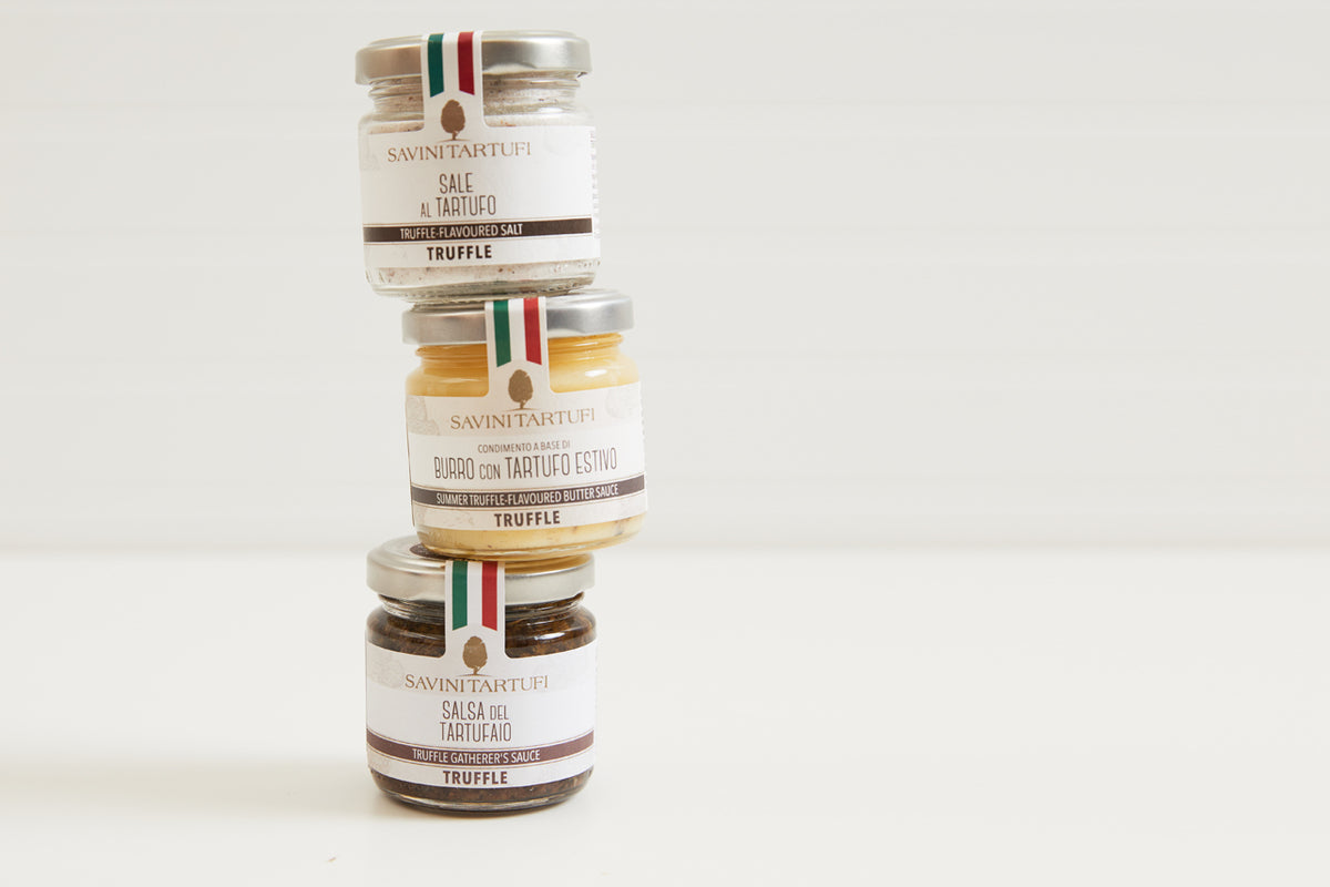 Three stacked glass jars of Savini Tartufi truffle products with Italian flag ribbons and cream-colored labels on white backg