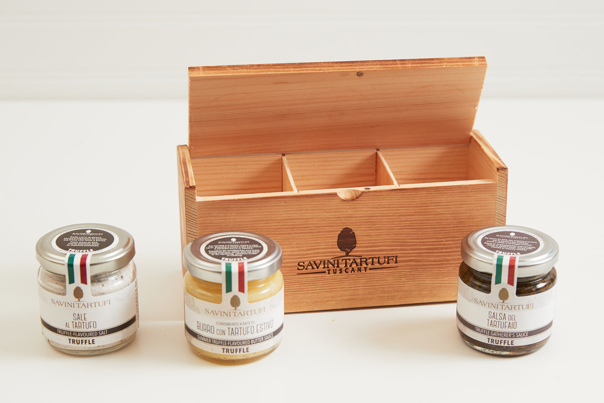 Wooden gift box with three glass jars of Savini Tartufi truffle products with metal lids and Italian flag ribbons.