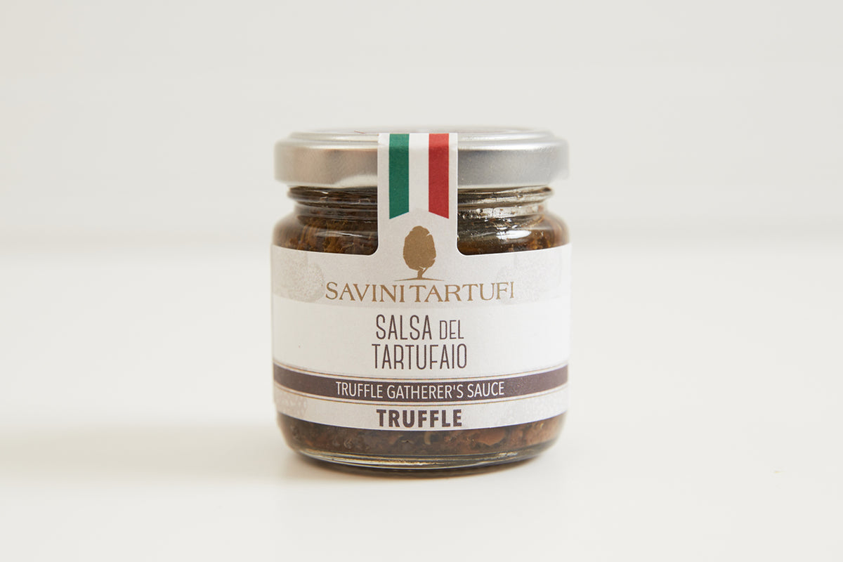 Glass jar of Savini Tartufi truffle sauce with cream label, Italian flag, and dark truffle pieces visible inside.