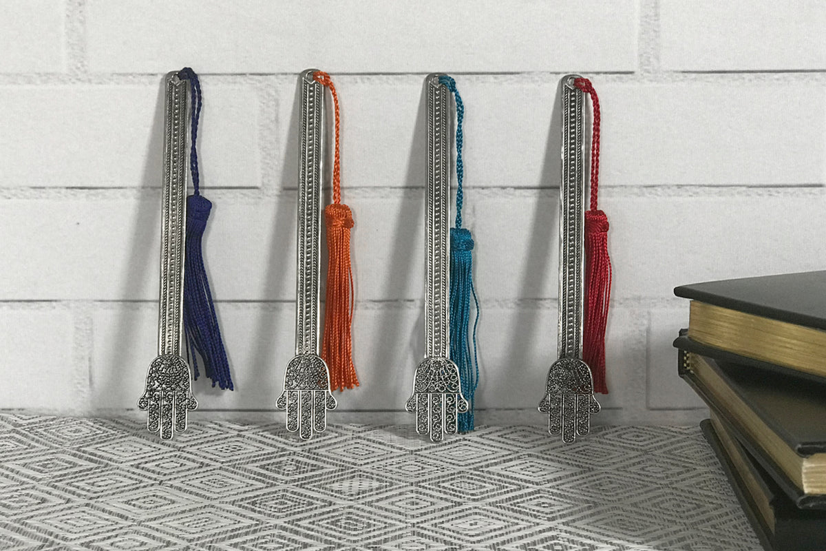 Four metal Hand of Fatima bookmarks with patterned strips and colored tassels in navy, orange, teal, and burgundy.