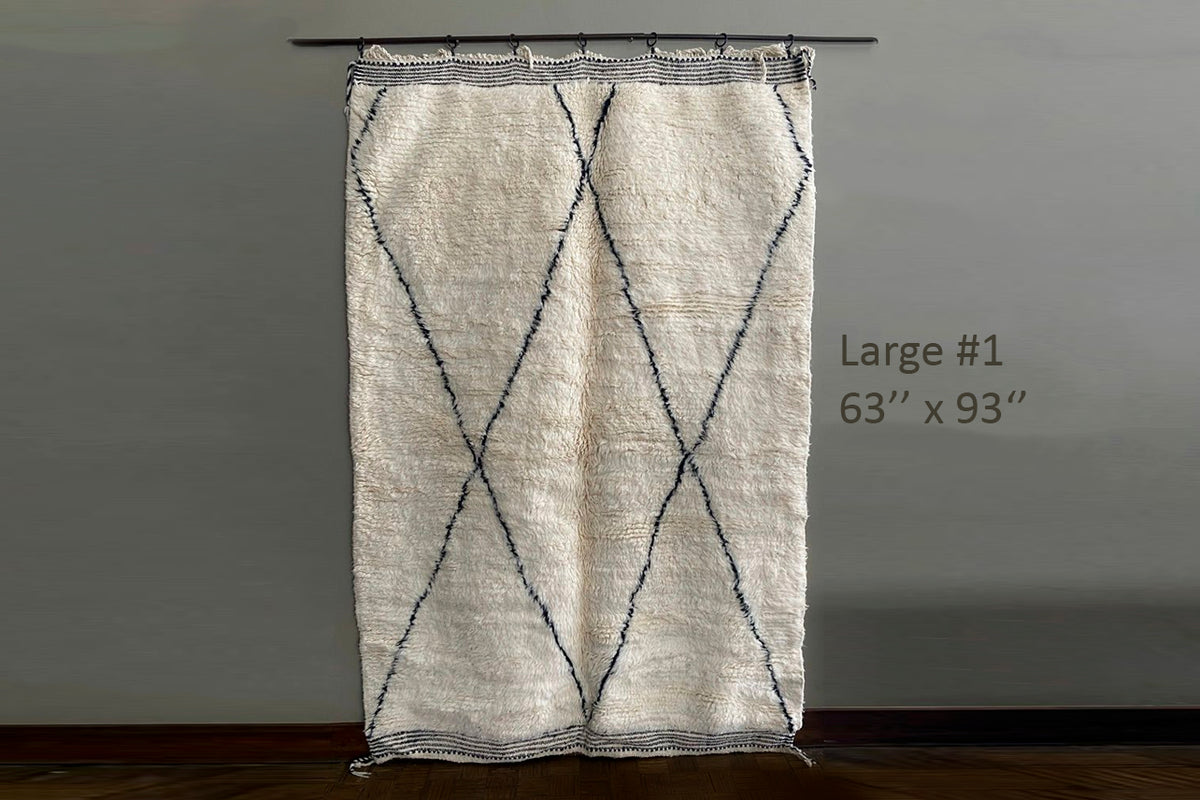 Cream-colored handwoven rug with dark diamond lattice pattern, displayed hanging, 63" x 93".