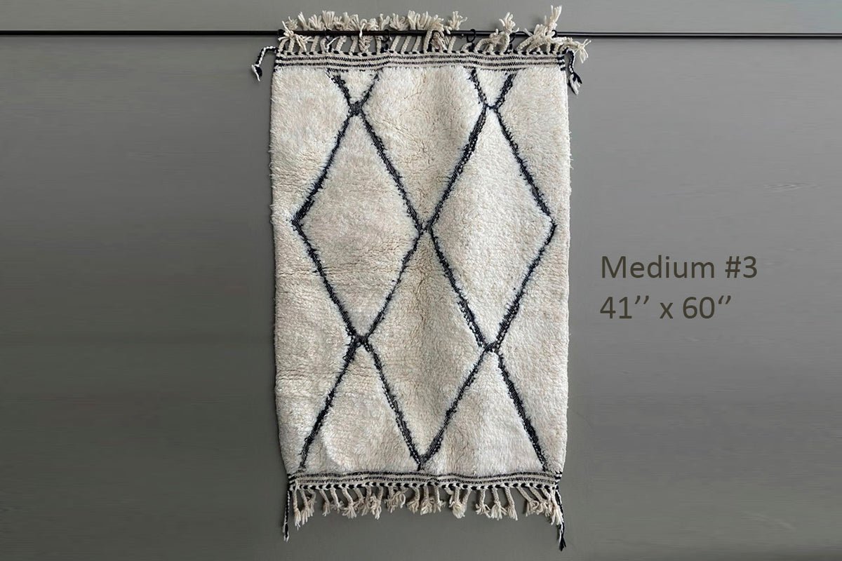 Cream-colored wool rug with black diamond lattice pattern and fringe trim on ends.