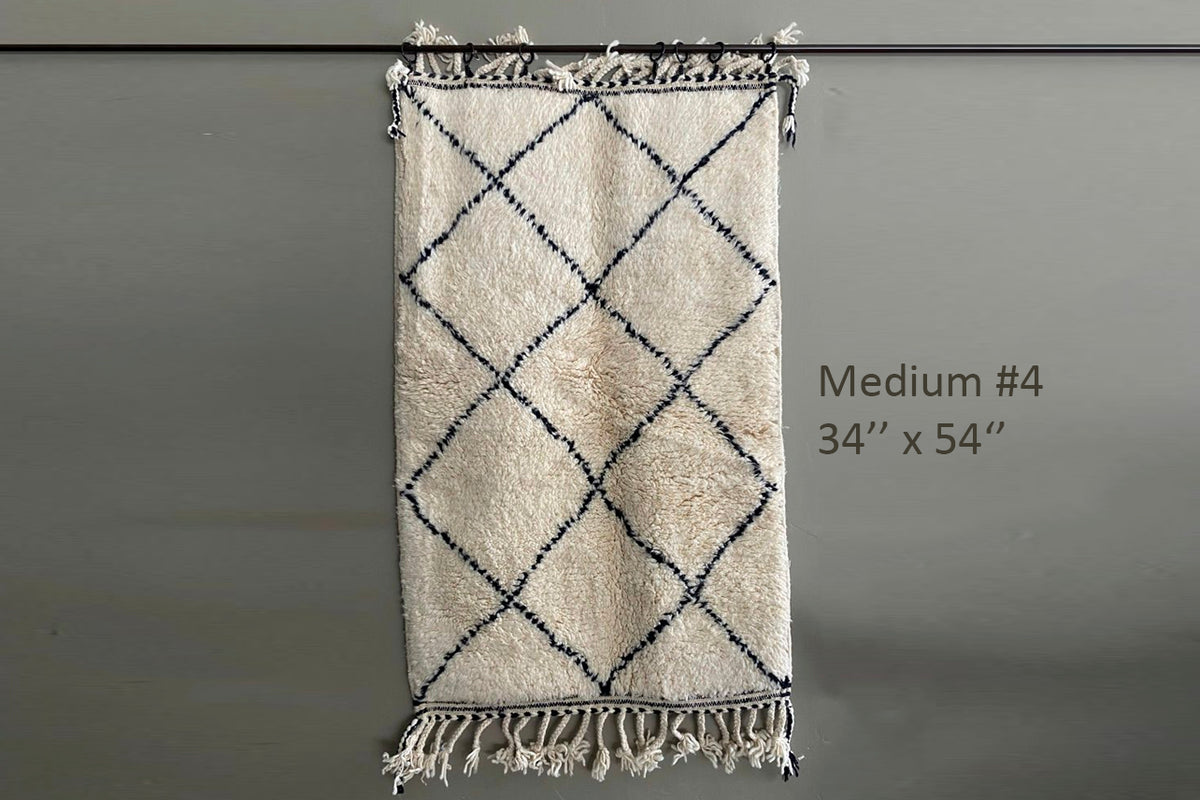 Cream wool rug with dark blue diamond lattice pattern and fringe trim along edges.