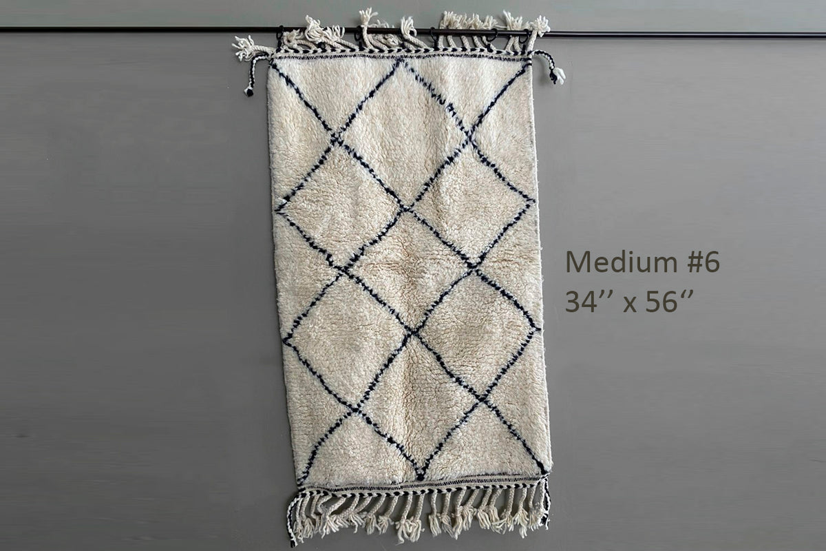 Cream-colored Berber rug with dark blue diamond pattern and fringed ends, 34" x 56".