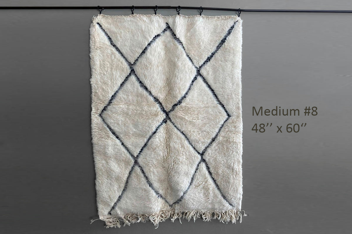 Cream-colored wool rug with dark blue diamond pattern and fringe edges, 48" x 60".