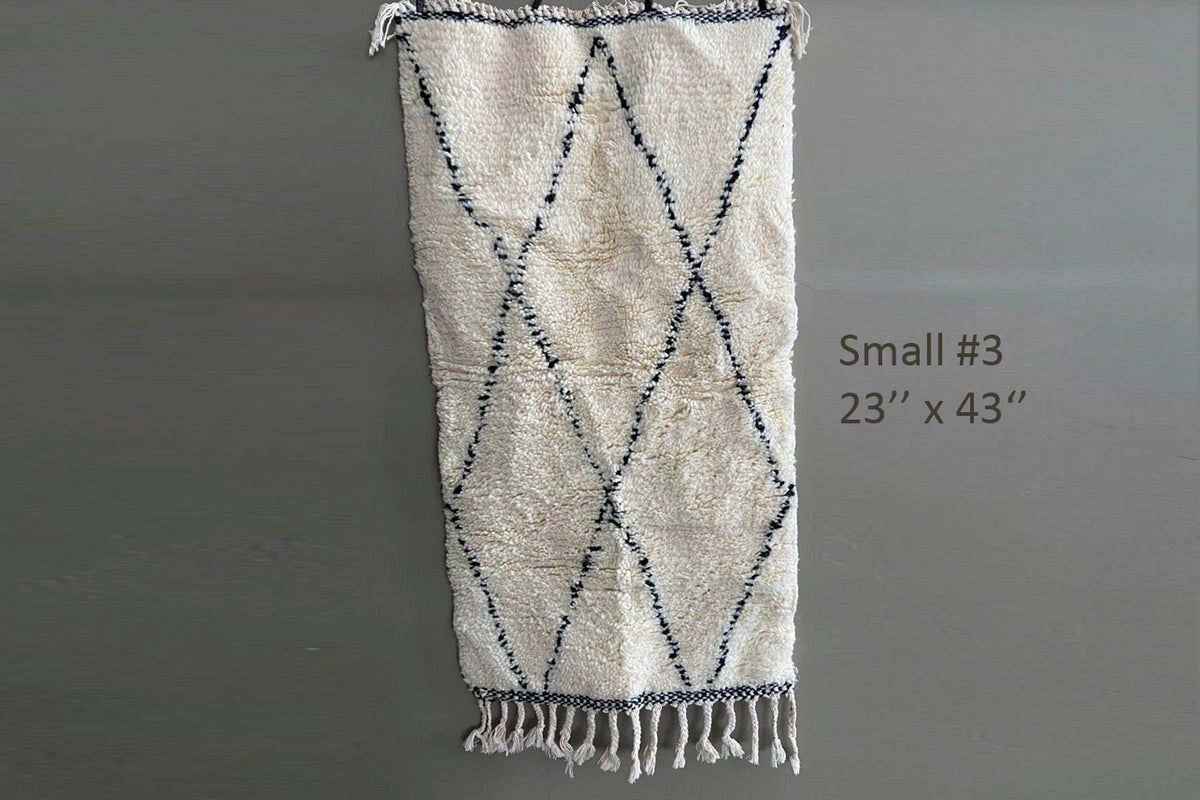Cream and navy diamond-patterned wool rug with fringe trim, 23" x 43".